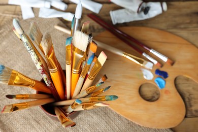 Photo of Many paintbrushes on wooden table, closeup. Space for text