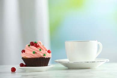 Photo of Delicious cupcake with pink cream and tea on white table