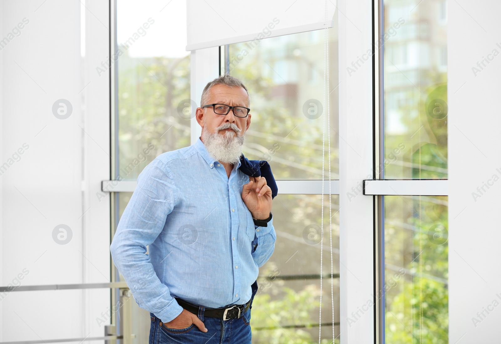 Photo of Portrait of handsome mature man with glasses and jacket near window