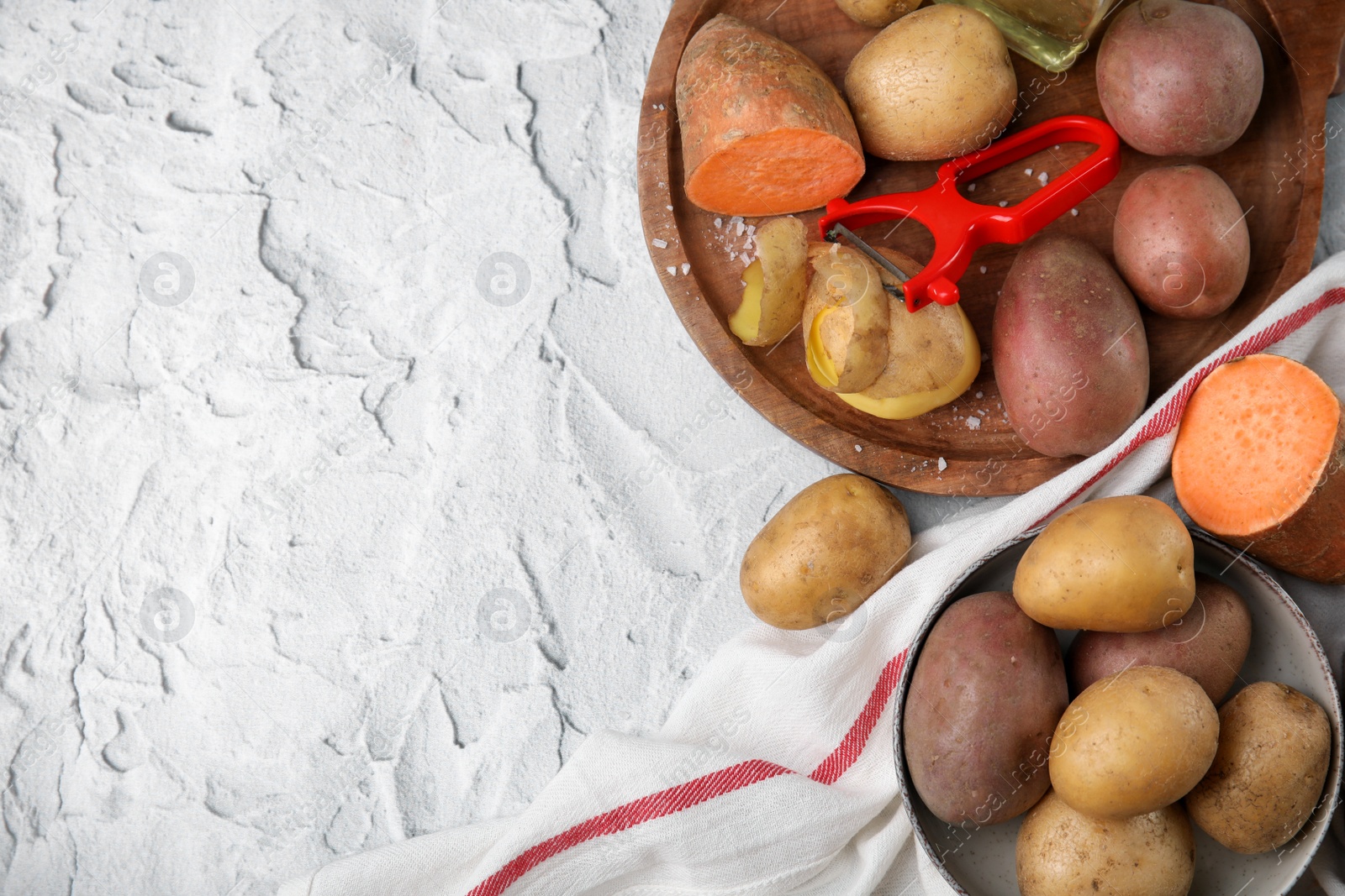 Photo of Different types of fresh potatoes on white textured table, flat lay. Space for text