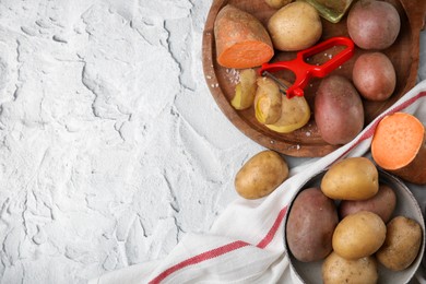 Different types of fresh potatoes on white textured table, flat lay. Space for text