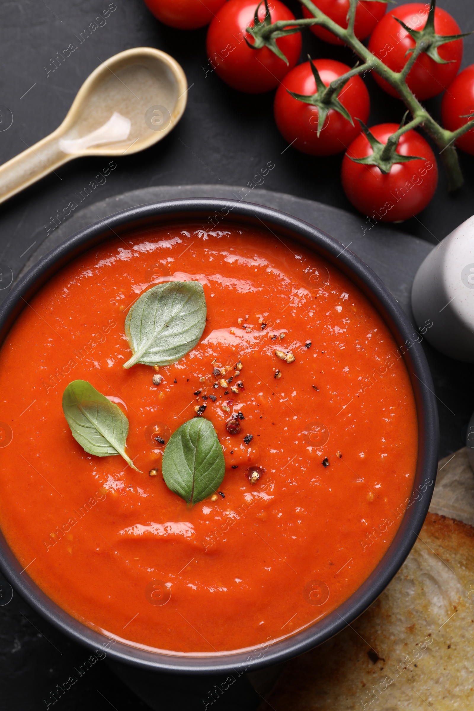 Photo of Delicious tomato cream soup served on black table, flat lay