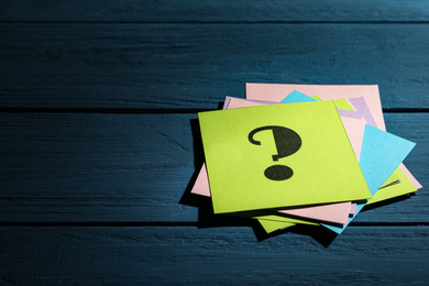 Photo of Paper cards with question mark on blue wooden background. Space for text
