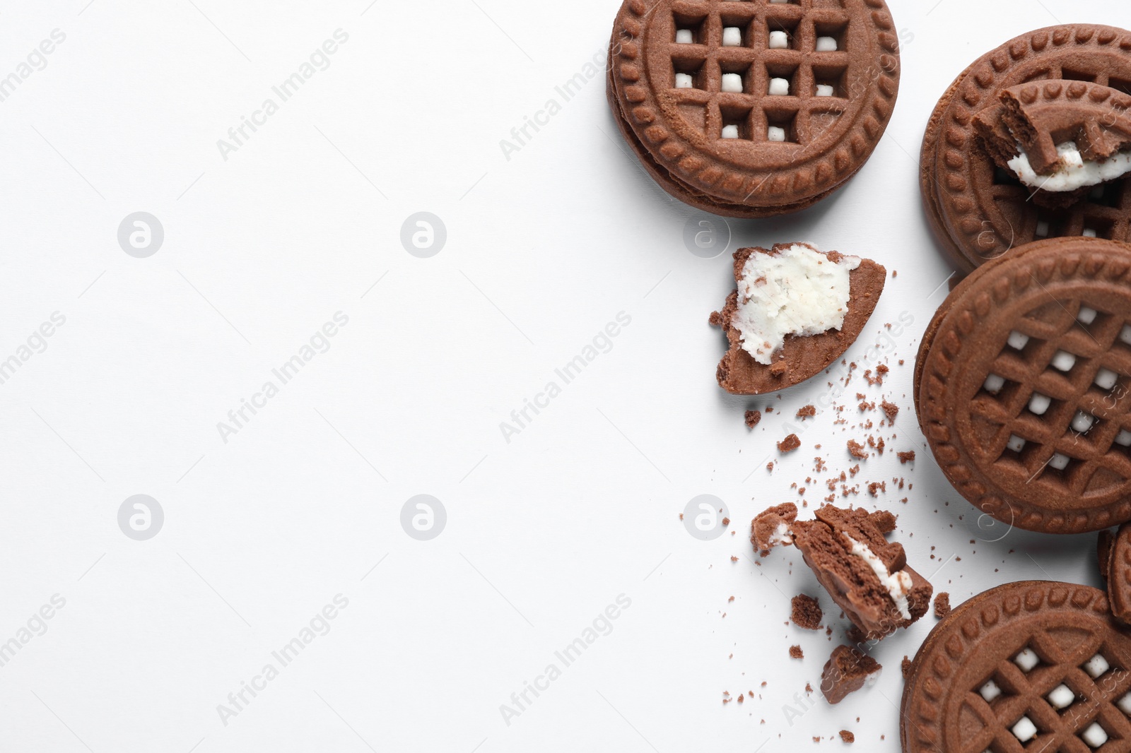 Photo of Tasty sandwich cookies with cream on white background, flat lay. Space for text