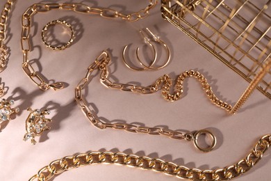 Photo of Metal chains and other different accessories on light brown background, above view. Luxury jewelry