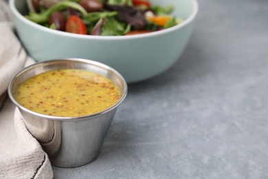 Photo of Tasty vinegar based sauce (Vinaigrette) in bowl on grey table, closeup. Space for text