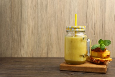 Photo of Tasty pineapple smoothie, mint and sliced fruit on wooden table. Space for text