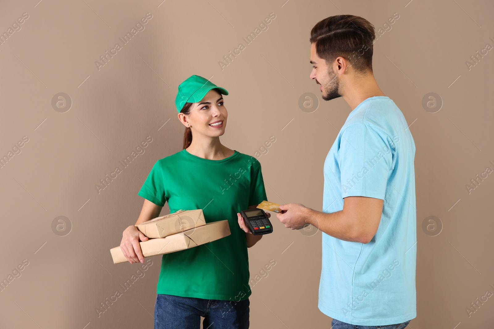 Photo of Young man with credit card using bank terminal for delivery payment on color background