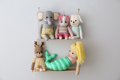 Photo of Shelf with cute toys on light wall. Child's room interior element