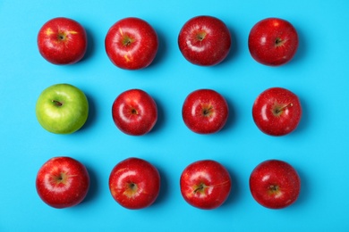 Green apple among red ones on color background, top view. Be different