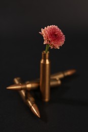 Bullets and cartridge case with beautiful flower on black background