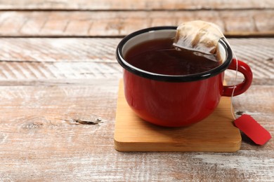 Tea bag in cup with hot drink on wooden rustic table. Space for text