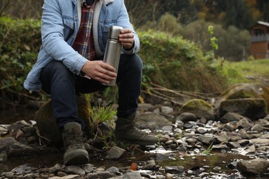 Photo of Man with metallic thermos in nature, closeup. Space for text