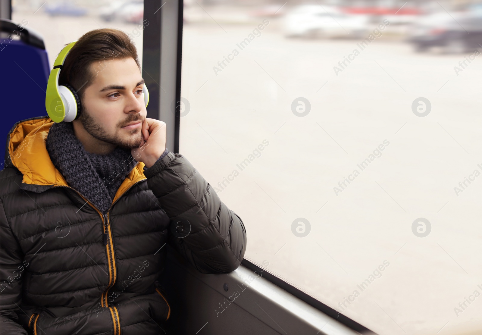 Photo of Young man listening to music with headphones in public transport