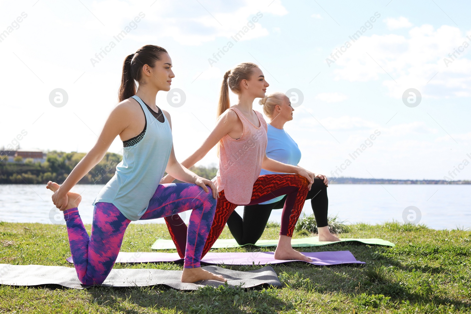 Photo of Group of women practicing yoga near river on sunny day