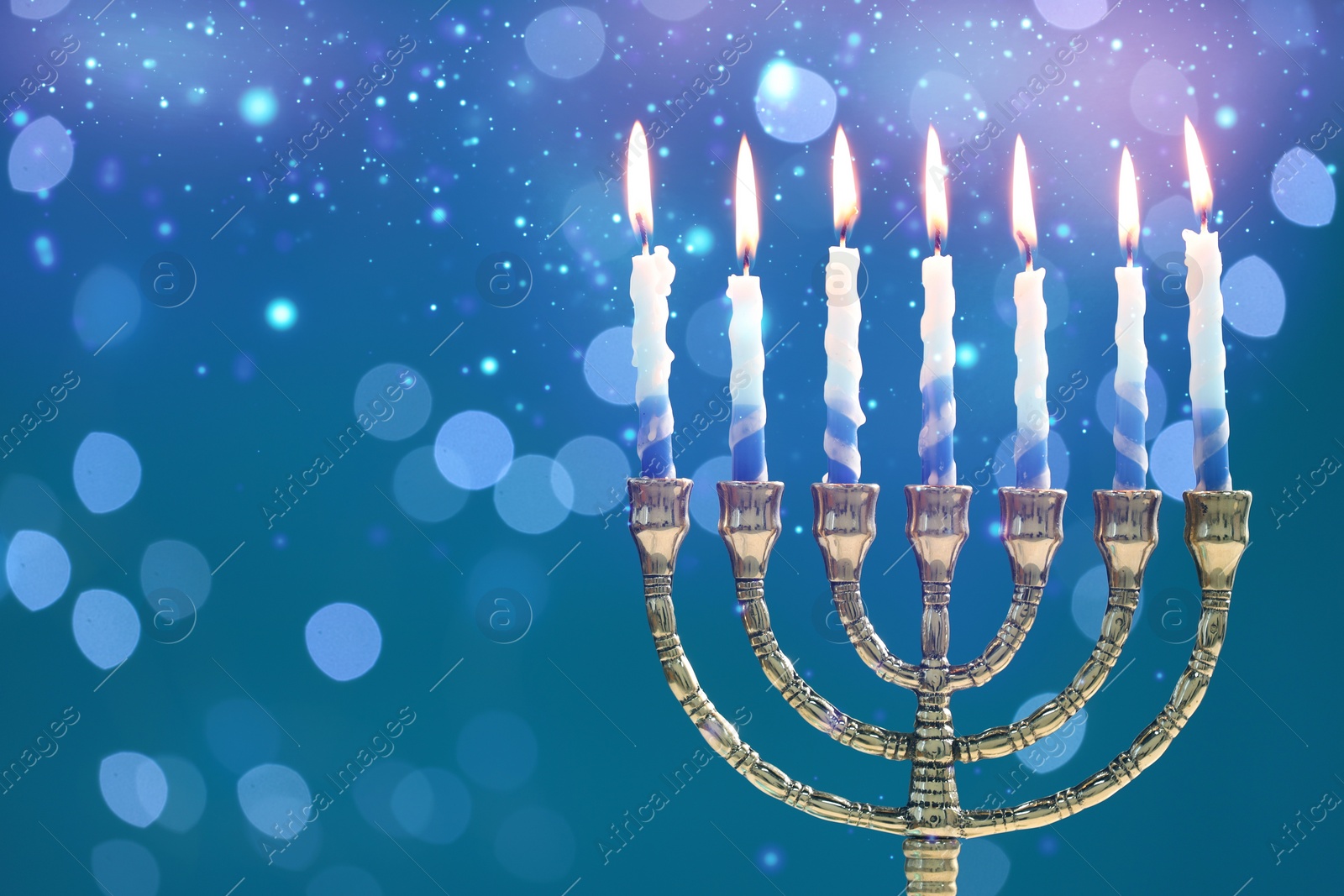 Image of Hanukkah celebration. Menorah with burning candles on blue background with blurred lights, space for text