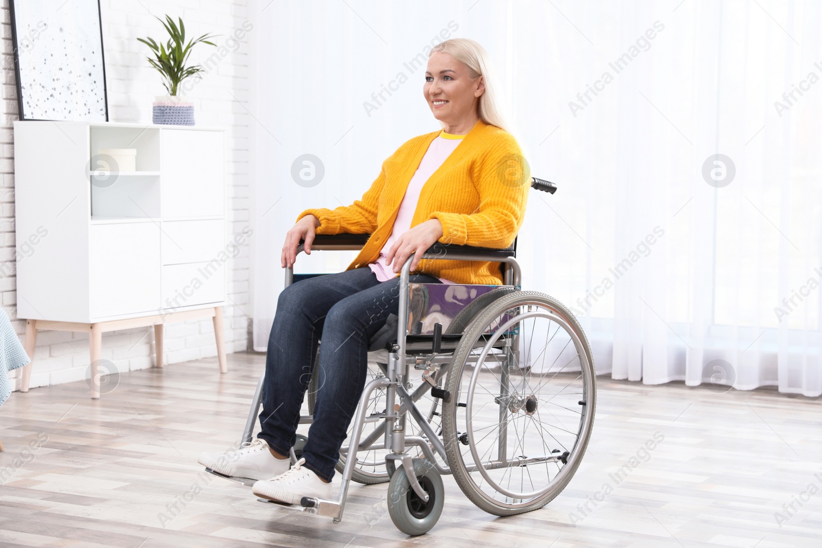 Photo of Mature woman sitting in wheelchair at home