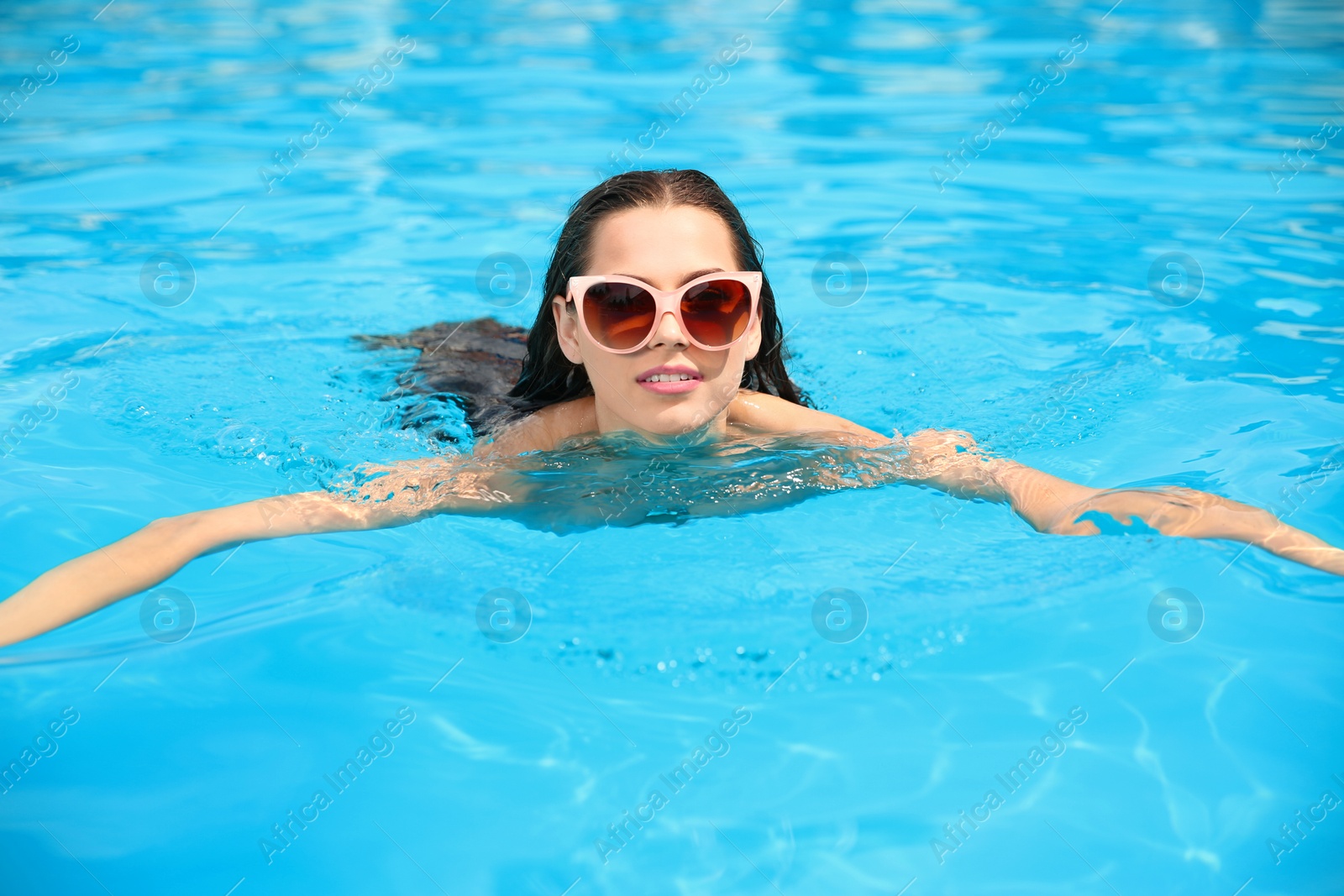 Photo of Beautiful young woman swimming in blue pool