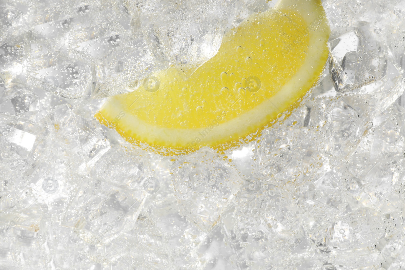 Photo of Juicy lemon slice and ice cubes in soda water on white background, closeup