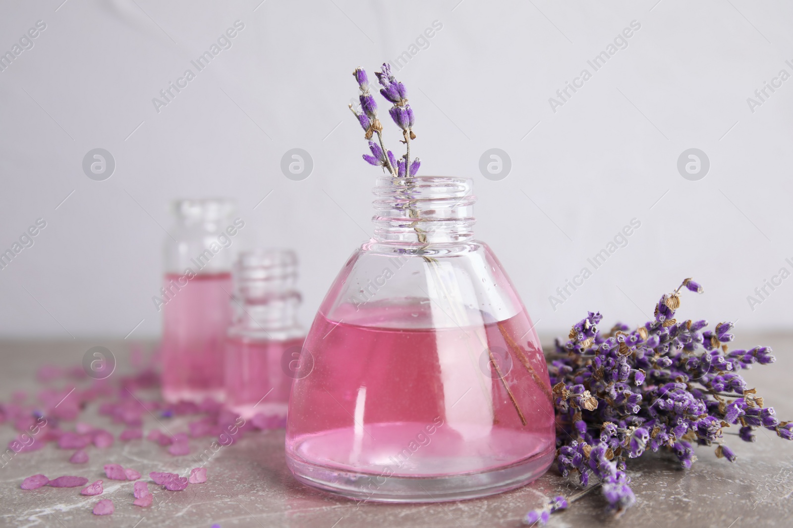 Photo of Bottles with aromatic lavender oil on grey table