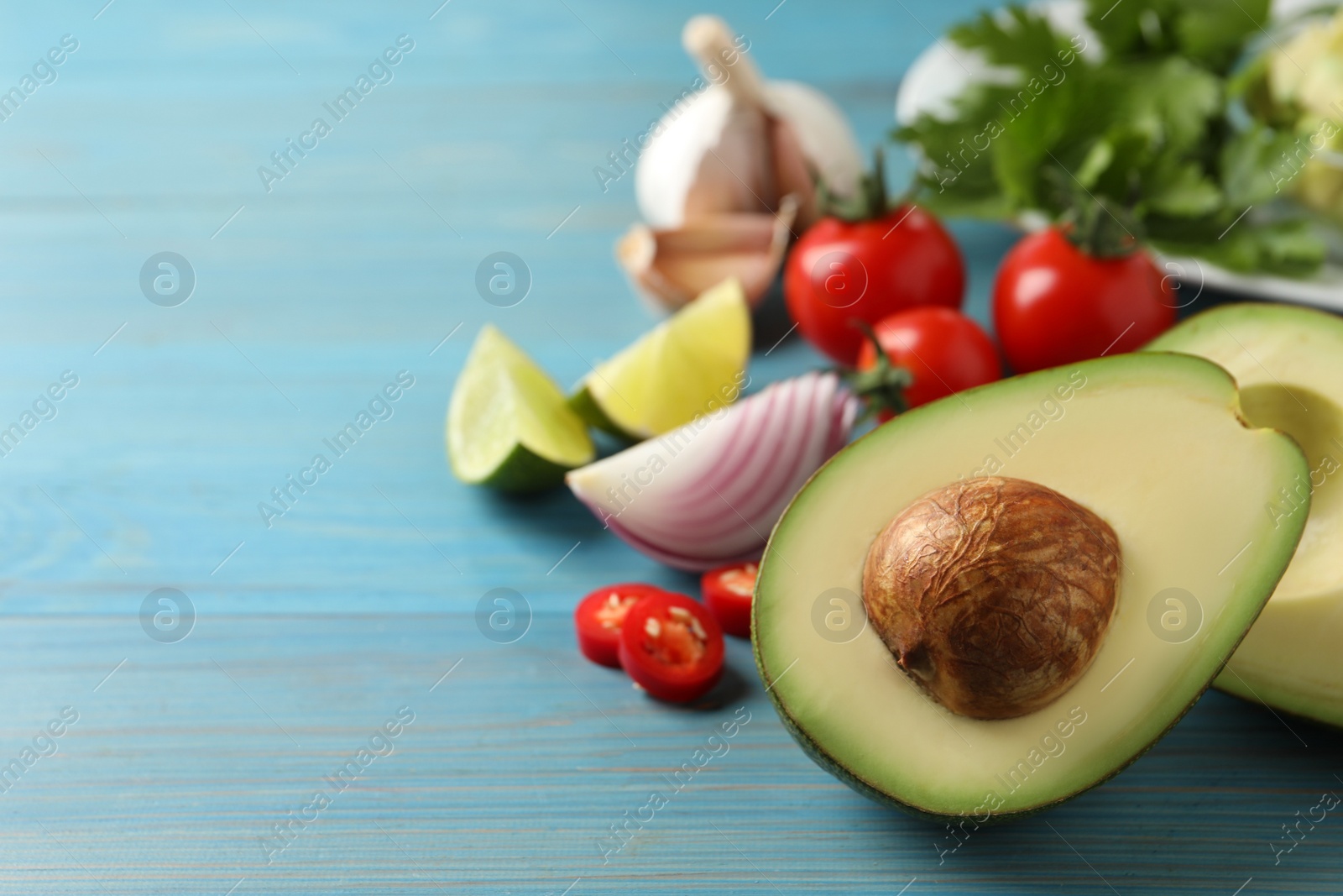 Photo of Fresh guacamole ingredients on light blue wooden table. Space for text