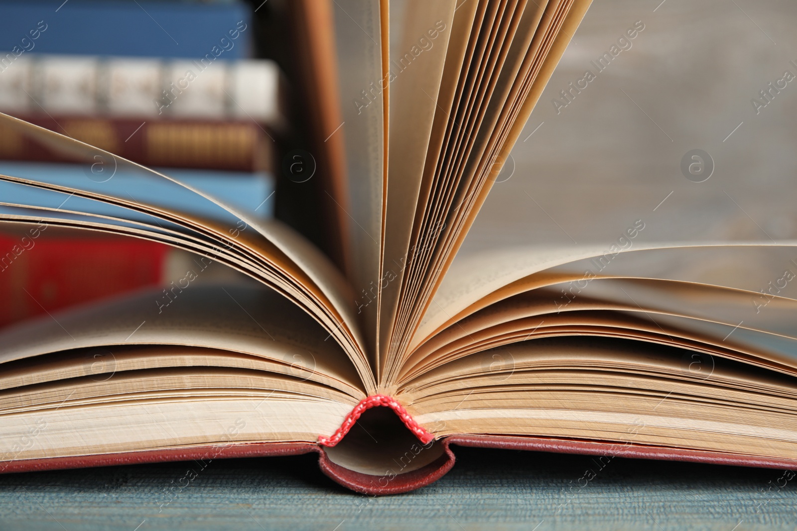 Photo of Open hardcover book on blue wooden table, closeup