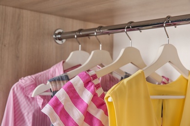 Photo of Stylish girl's clothes hanging in wardrobe, closeup