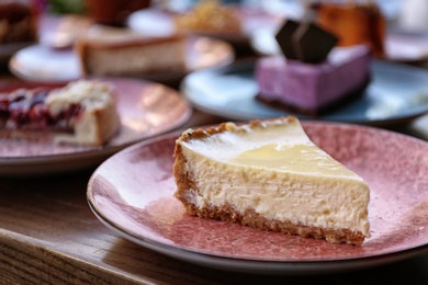 Photo of Plate with slice of cheesecake on wooden table