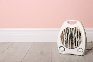 Photo of Modern electric fan heater on floor in room, space for text