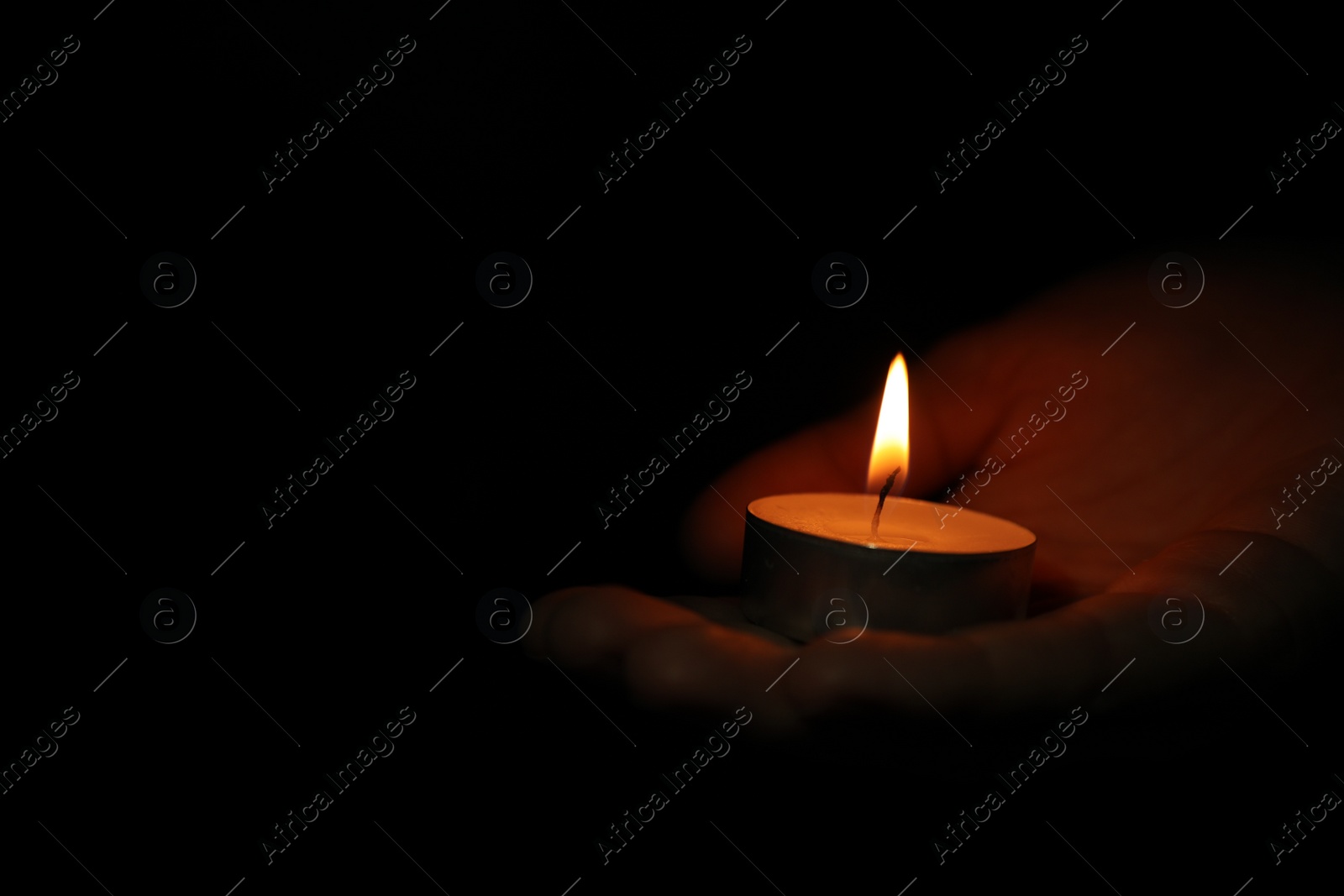 Photo of Woman holding burning candle in darkness, closeup. Space for text