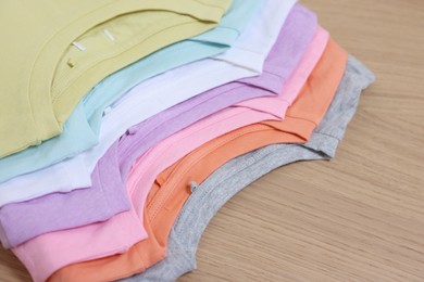 Photo of Many stacked clothes on wooden table, closeup