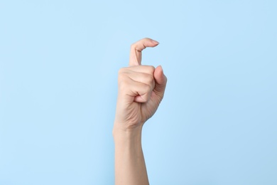 Photo of Woman showing X letter on color background, closeup. Sign language