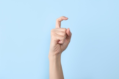 Woman showing X letter on color background, closeup. Sign language