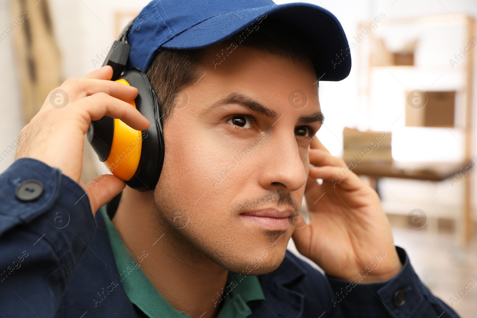 Photo of Worker wearing safety headphones indoors. Hearing protection device