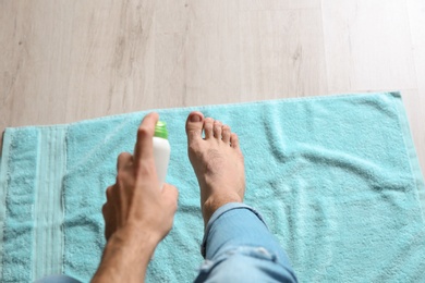 Young man using deodorant for feet at home, closeup