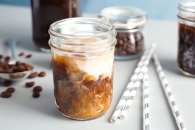 Photo of Jar with cold brew coffee and milk on table