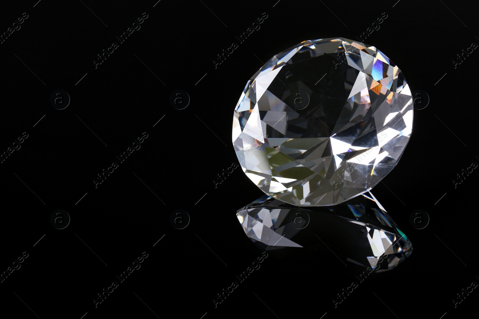 Photo of Beautiful shiny diamond on black mirror surface, closeup. Space for text