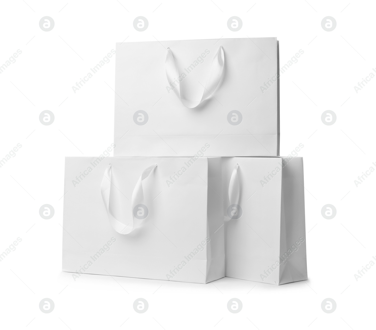 Photo of Paper shopping bags with ribbon handles on white background. Mockup for design