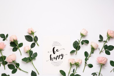 Photo of Frame of beautiful flowers and paper card with handwritten text Be happy on white background, flat lay