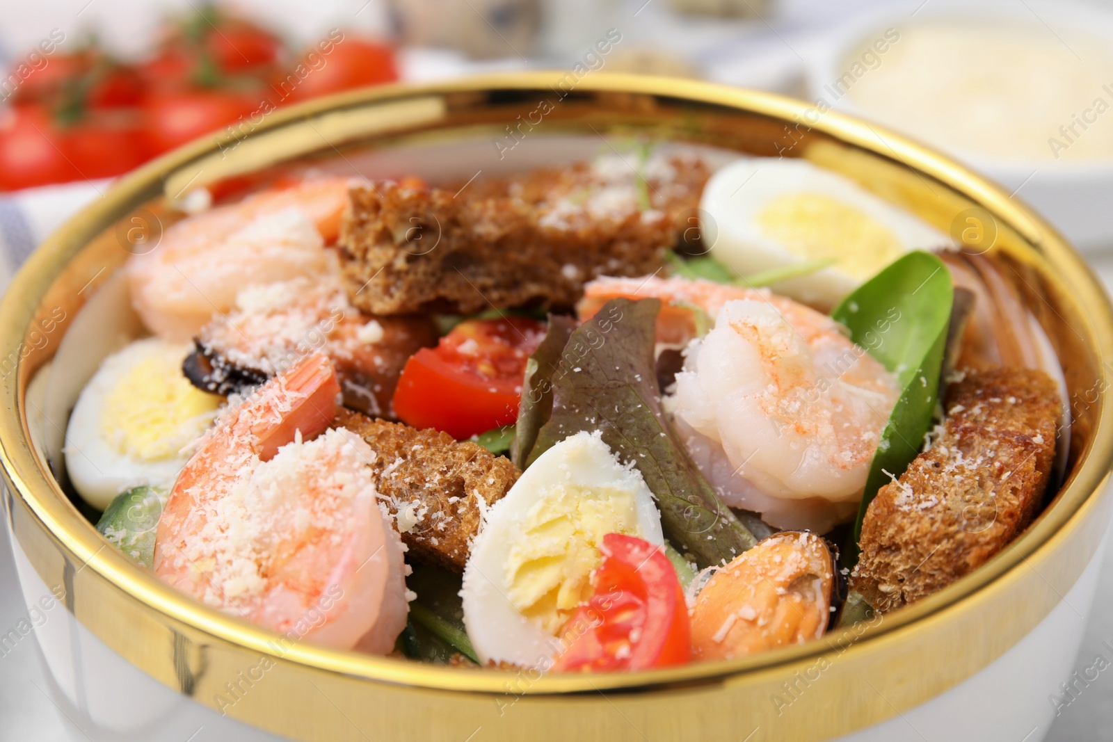 Photo of Delicious salad with croutons, tomatoes and shrimp served on table, closeup