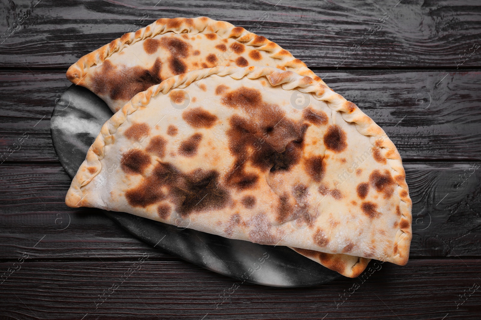 Photo of Delicious calzones on wooden table, top view
