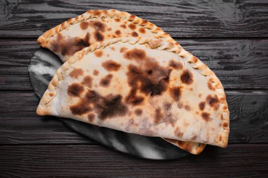 Photo of Delicious calzones on wooden table, top view