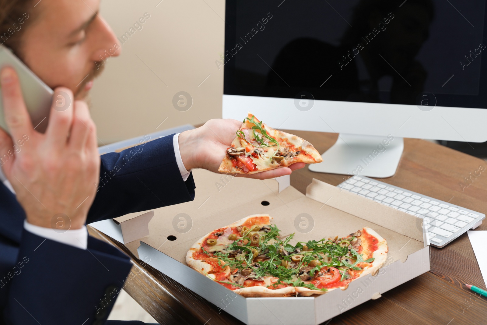 Photo of Office employee having pizza for lunch at workplace, closeup. Food delivery