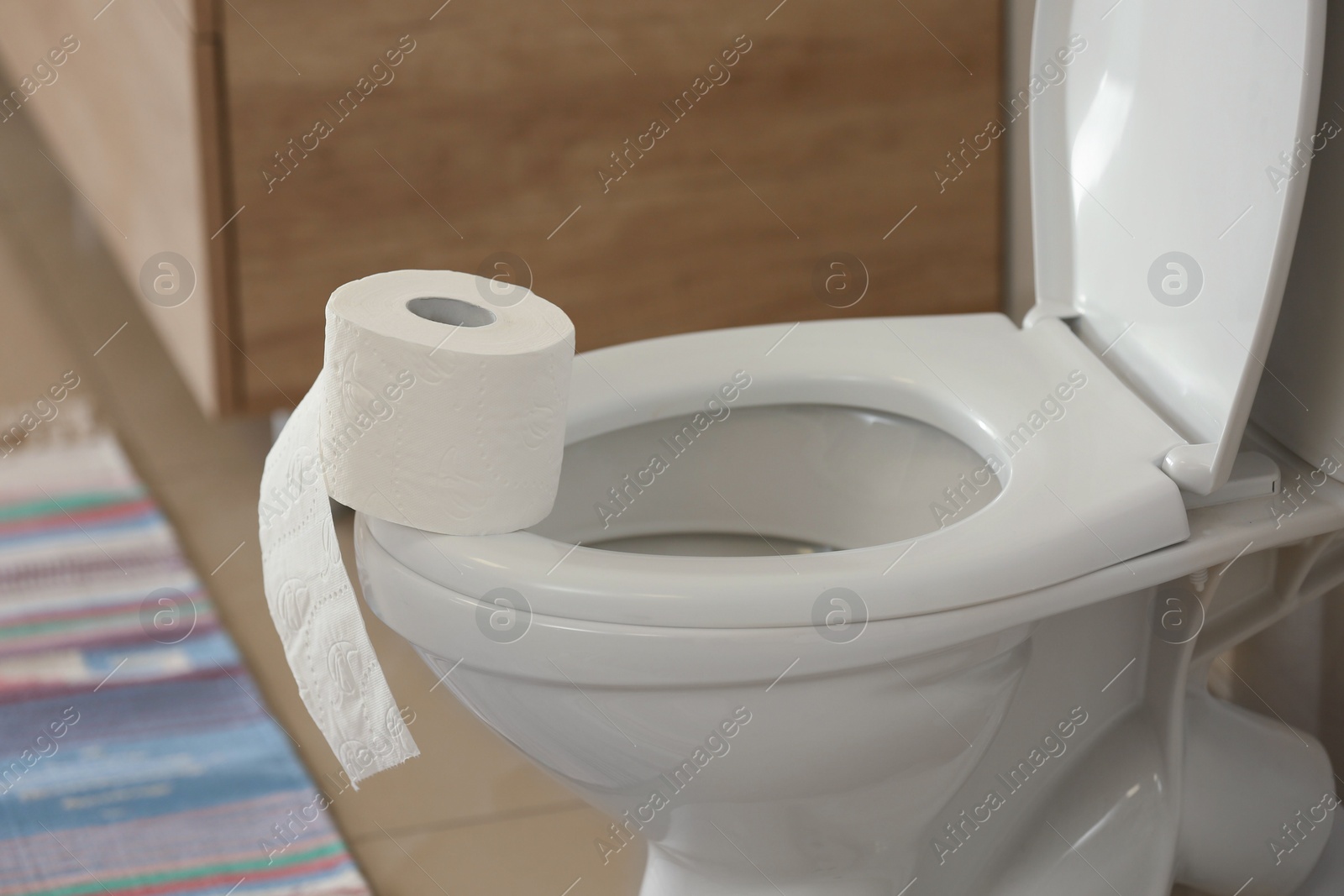 Photo of Modern toilet bowl with roll of paper in bathroom