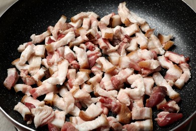 Photo of Cooking cracklings in frying pan, closeup. Pork lard