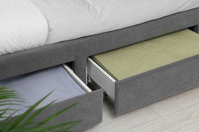 Storage drawers with bedding under comfortable bed in room