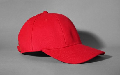 Stylish red baseball cap on grey background