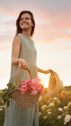 Woman with basket of roses in beautiful blooming field