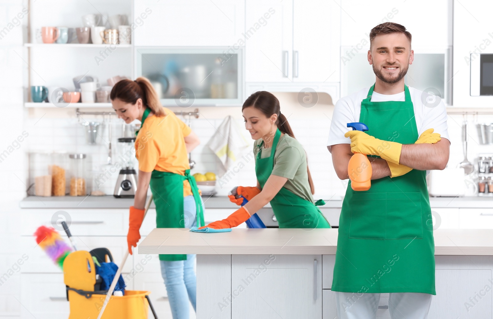 Photo of Team of professional janitors in uniform cleaning kitchen