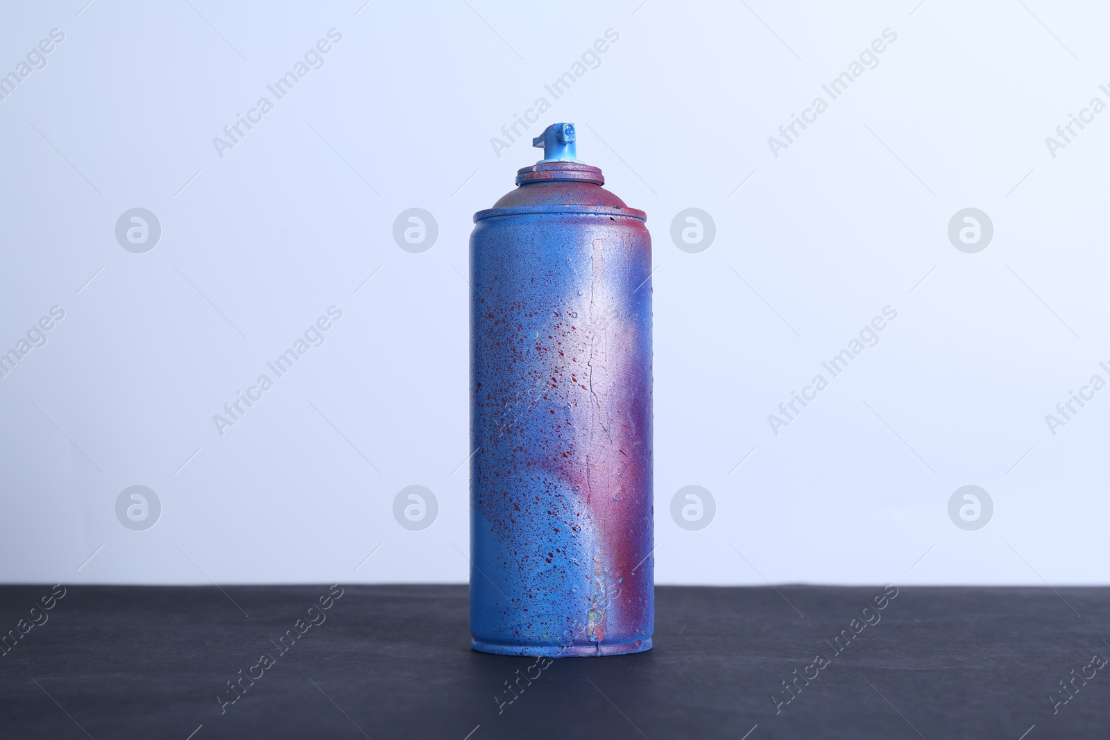 Photo of Spray paint can on black surface against white background